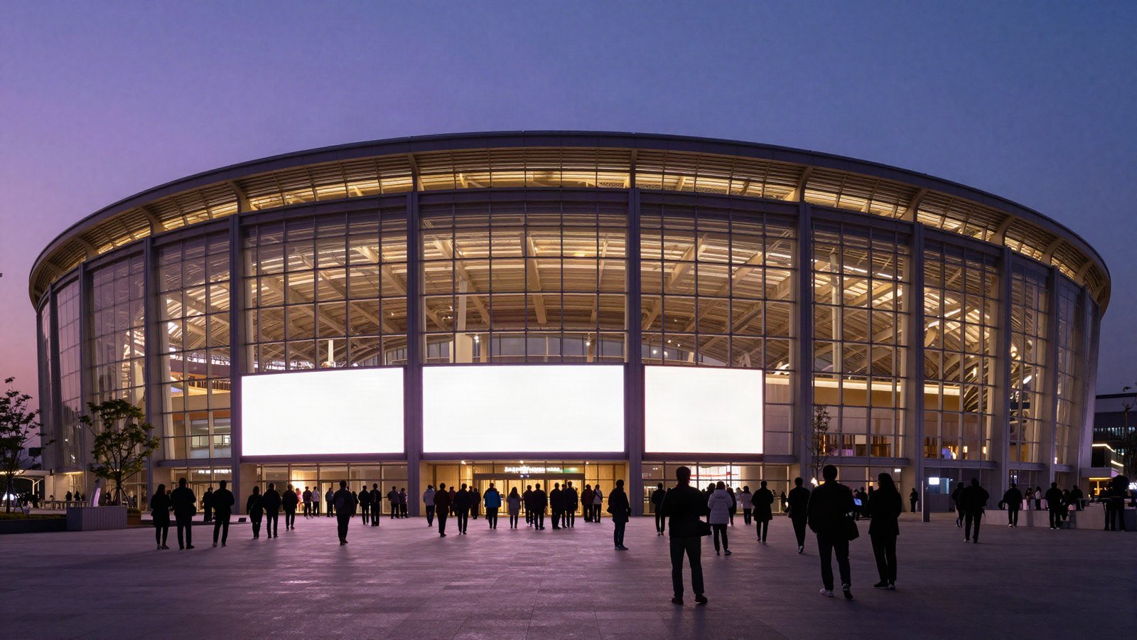 A large arena lit in purple and gold at dusk as crowds gather outside