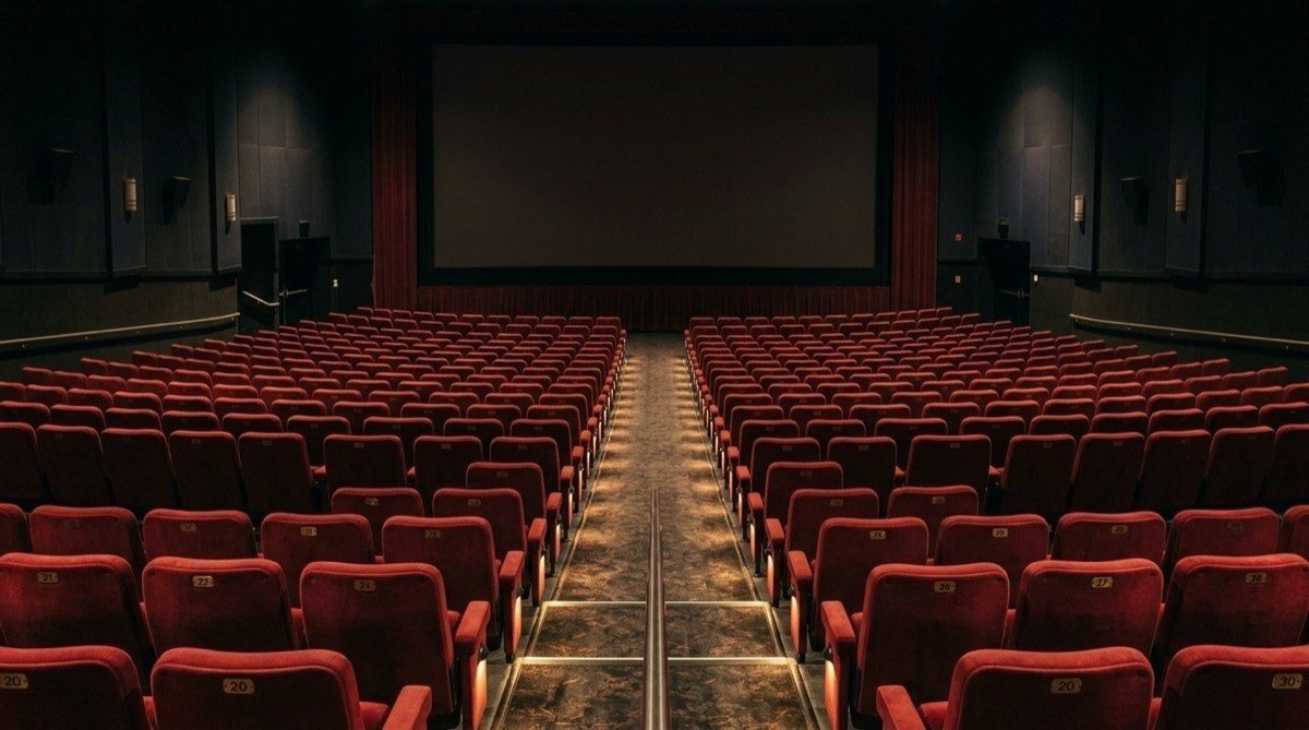 Rows of empty red seats facing the screen inside a movie theater