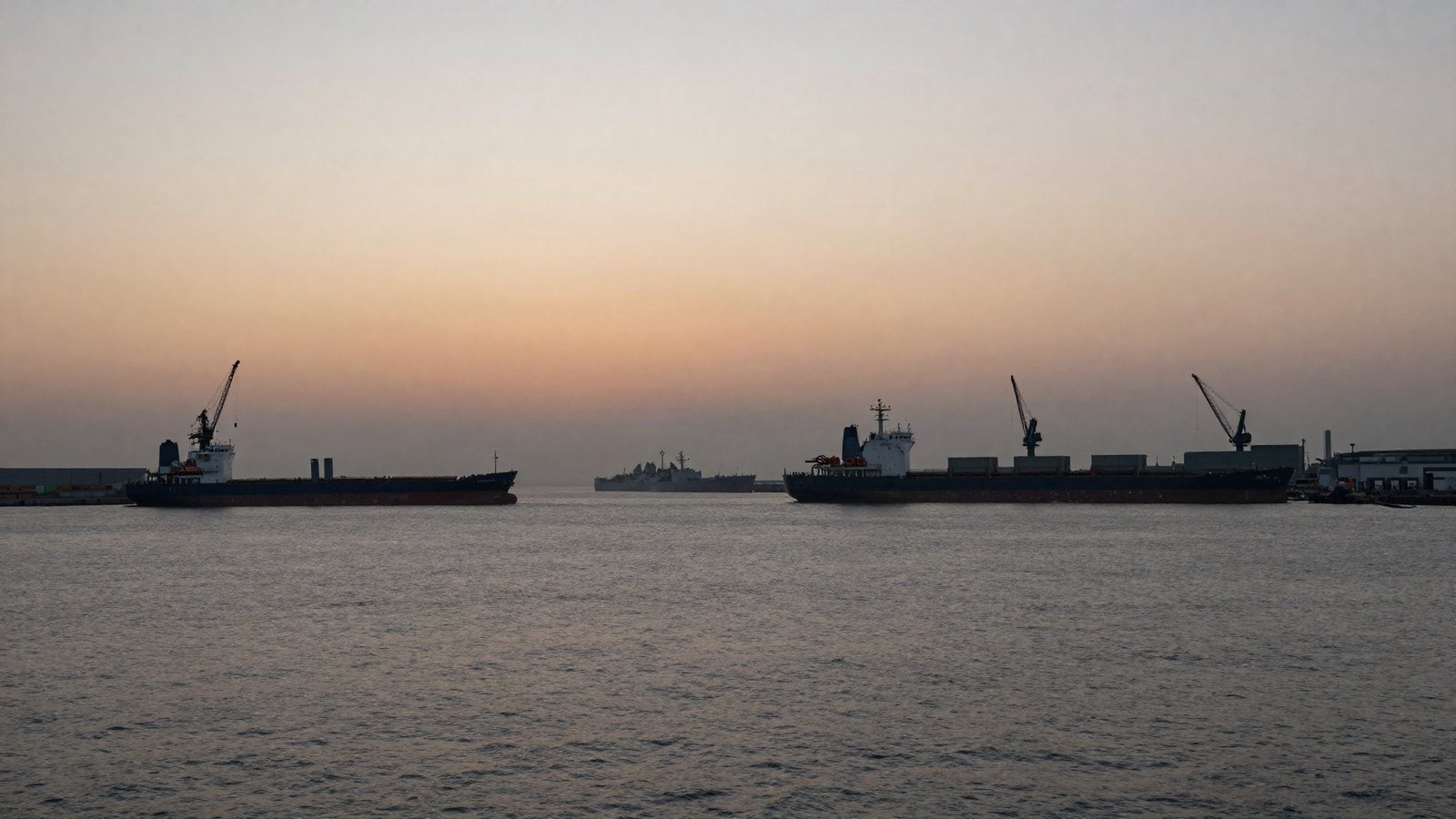 Ships silhouetted at anchor in a hazy Black Sea port at dawn