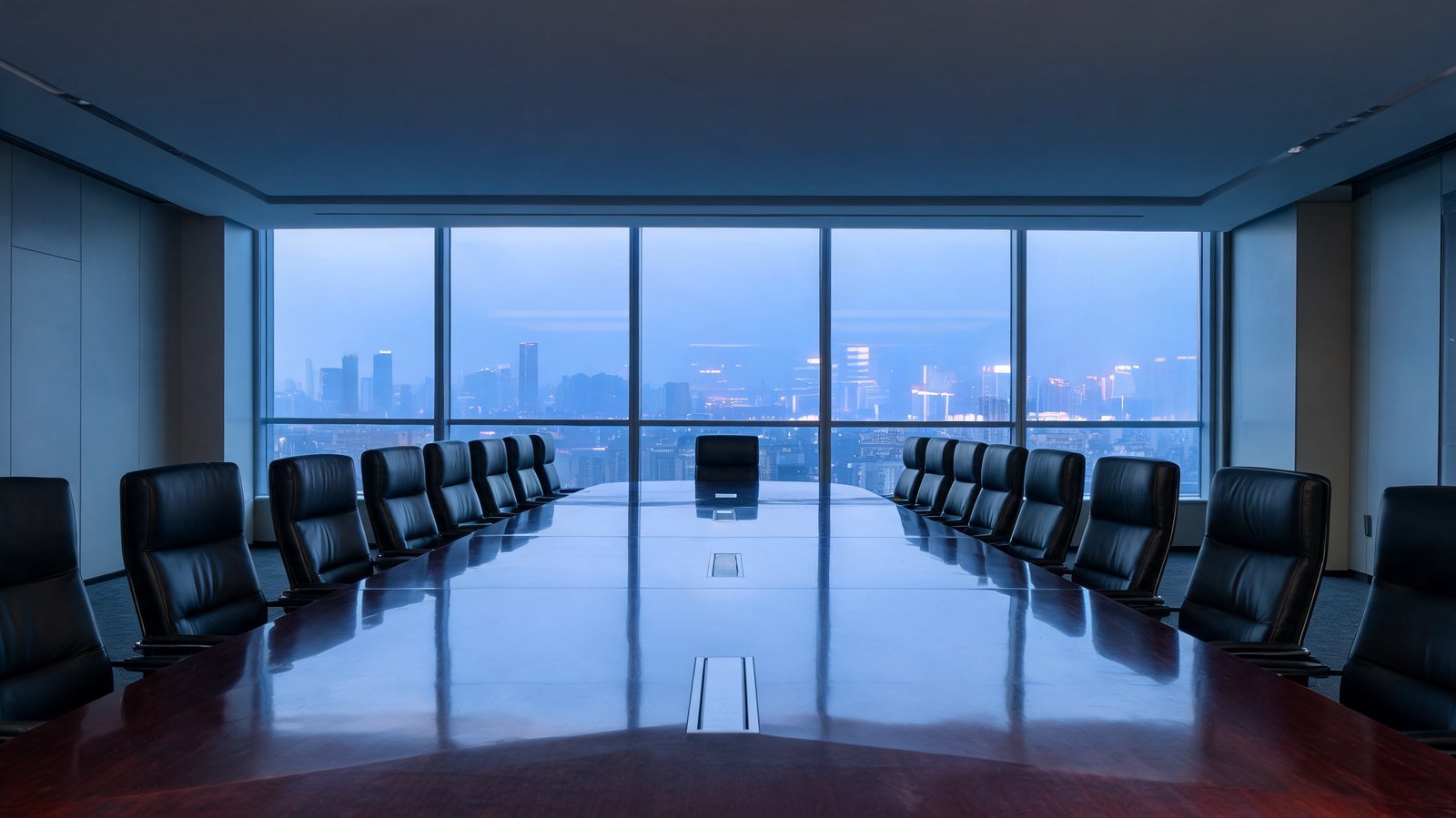 An empty corporate boardroom at dusk with a city skyline beyond